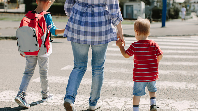 Mother walking two young sons across a street