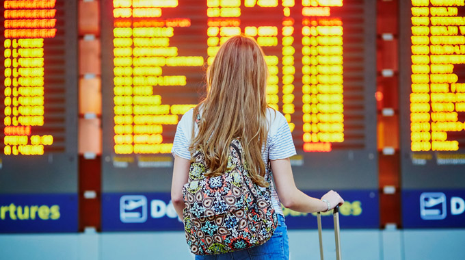 A woman looks at an airport flight information board