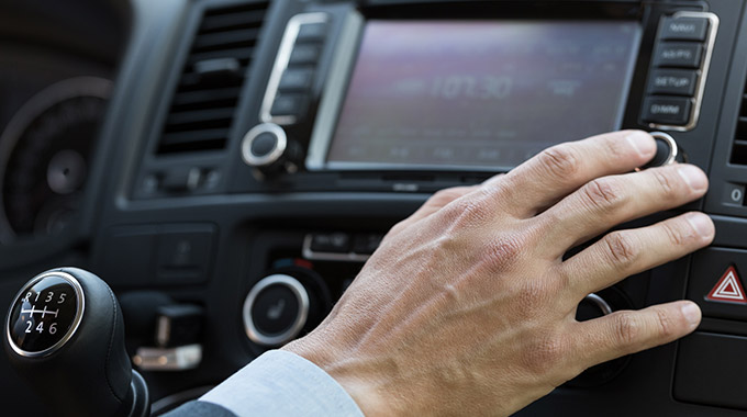 Hand adjusting stereo radio controls in a car