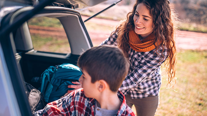 A mother and son pack their car for a road trip.