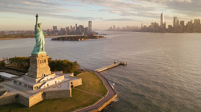 The Statue of Liberty in New York Harbor with Manhattan in the background at sunrise