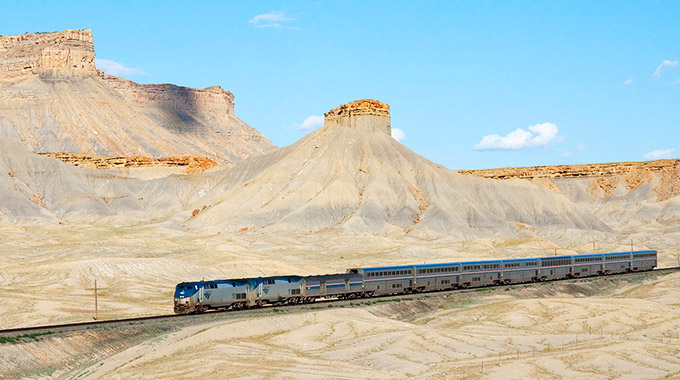 The California Zephyr Amtrak train travels through a red rock landscape in Utah