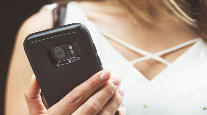 A woman holding a phone in a black OtterBox case