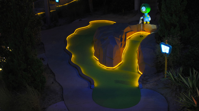 Alien minigolf course lit up yellow at night