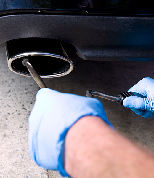 Mechanic taking emission samples from car tailpipe as part of a smog check