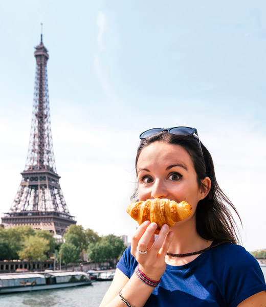 Woman eating croissant with Eiffel Tower in background