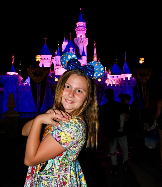Charlie posing at night in front of Sleeping Beauty Castle at Disneyland Resort