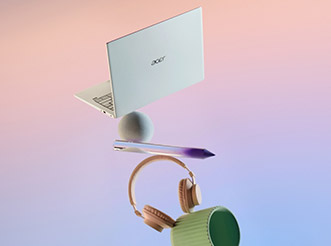 An Acer laptop balanced atop a tablet and a pair of headphones