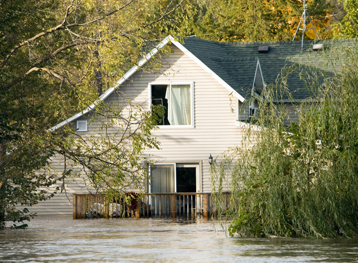 An outside view of a home sitting in floodwater An outside view of a home sitting in floodwater