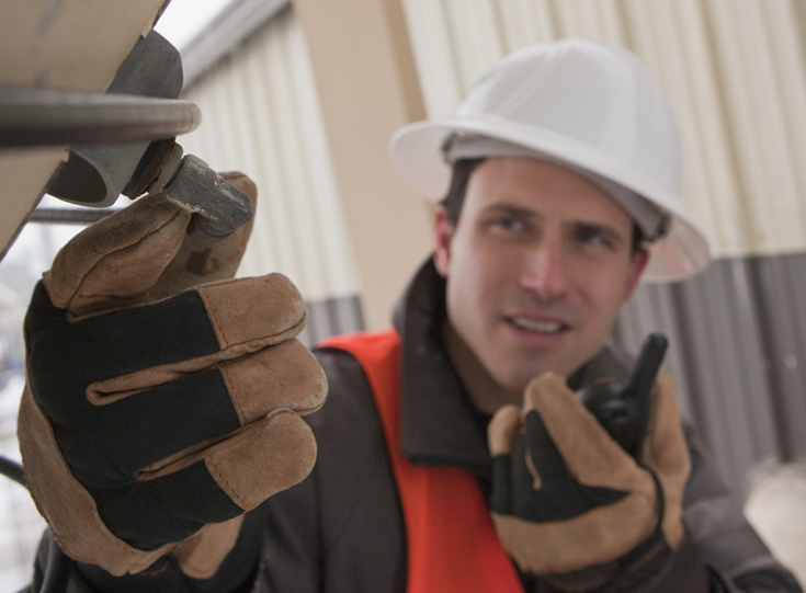 Contractor talks into 2-way radio while inspecting outside of building Contractor talks into 2-way radio while inspecting outside of building