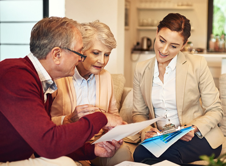 Older couple looking at documents together with a representative in their home Older couple looking at documents together with a representative in their home