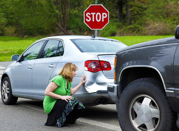 Woman looking at car damage after accident Woman looking at car damage after accident