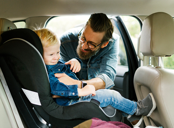 Man helping child into car seat Man helping child into car seat