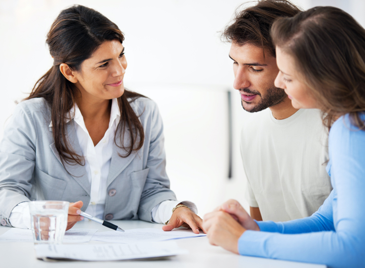 A couple reviews paperwork with an agent A couple reviews paperwork with an agent