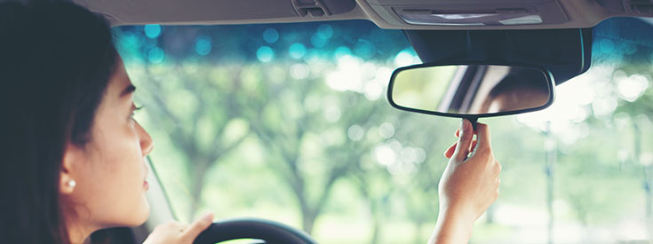 A woman in a car adjusts her rear-view mirror. A woman in a car adjusts her rear-view mirror.