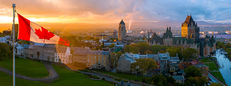 View of the Chateau Frontenac, a Canadian flag, and Quebec City at sunset. View of the Chateau Frontenac, a Canadian flag, and Quebec City at sunset.
