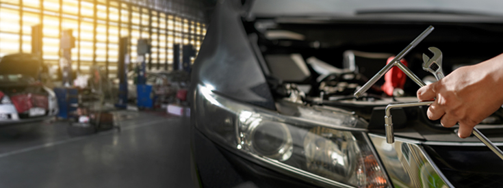 Car in repair bay mechanic holding tools Car in repair bay mechanic holding tools