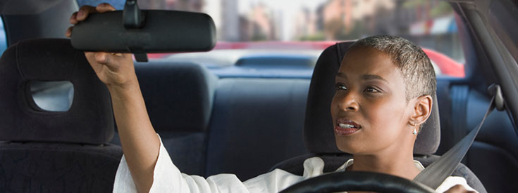 Woman adjusting rear view mirror Woman adjusting rear view mirror
