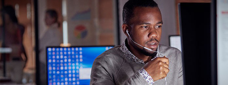Call center agent looking at computer screen while taking a call Call center agent looking at computer screen while taking a call