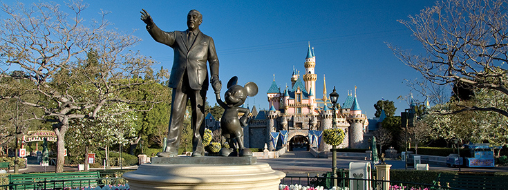 A statue of Walt Disney holding hands with Mickey Mouse in front of Sleeping Beauty Castle at Disneyland park A statue of Walt Disney holding hands with Mickey Mouse in front of Sleeping Beauty Castle at Disneyland park