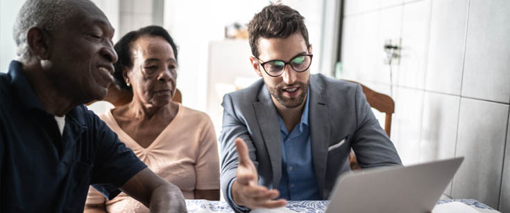 Agent reviewing policy on a laptop with couple Agent reviewing policy on a laptop with couple