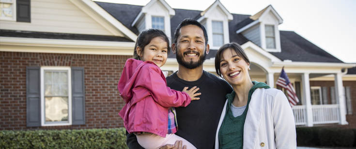 Woman and man carrying young girl stand in front of their house Woman and man carrying young girl stand in front of their house
