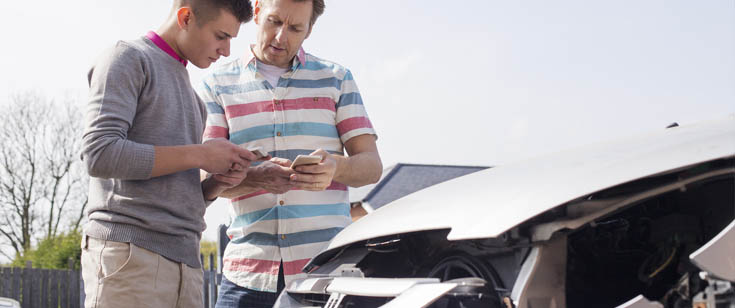Claims agent taking notes while inspecting a damaged vehicle Claims agent taking notes while inspecting a damaged vehicle