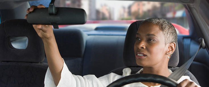 Woman adjusting rear view mirror Woman adjusting rear view mirror
