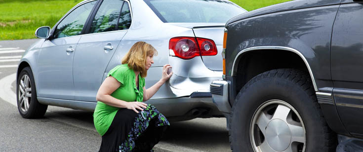 Woman looking at car damage after accident Woman looking at car damage after accident