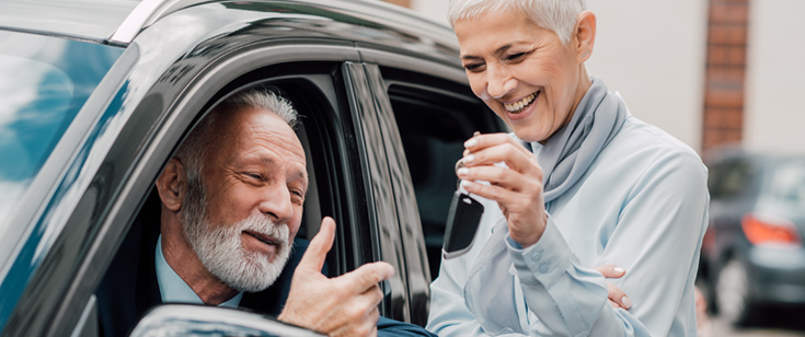Woman handling keys to man behind the wheel of a vehicle Woman handling keys to man behind the wheel of a vehicle