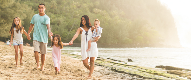 Family of 5 holding hands while walking on the beach