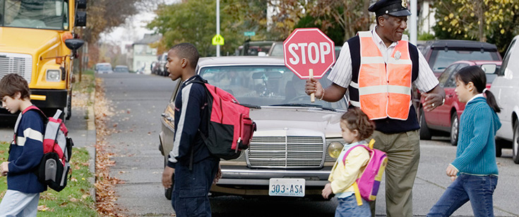 Crossing guard holds stop sign while chidren cross the street. Crossing guard holds stop sign while chidren cross the street.