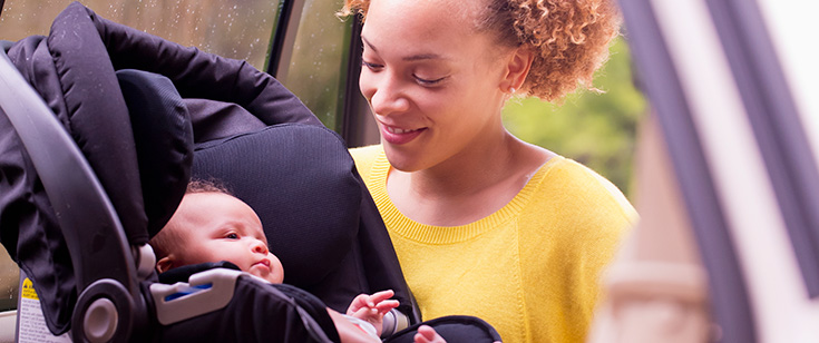 Woman buckling baby into car seat. Woman buckling baby into car seat.