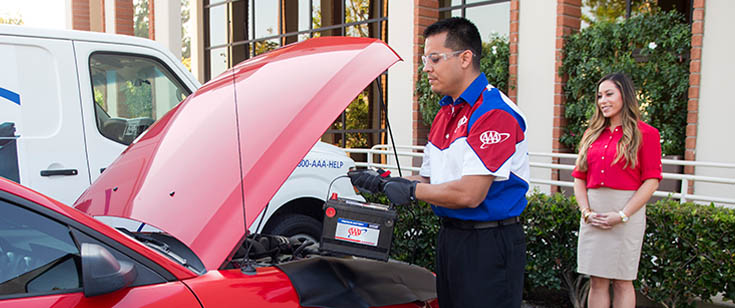 Member watching as a AAA technician replaces a vehicle battery Member watching as a AAA technician replaces a vehicle battery