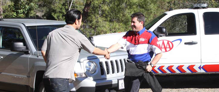 AAA Roadside Assistance driver shaking hands with member waiting beside vehicle AAA Roadside Assistance driver shaking hands with member waiting beside vehicle