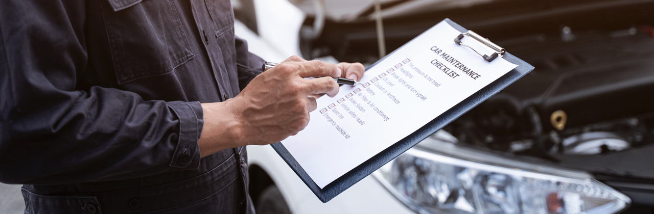 Hands holding car mainternance checklist on clipboard, Car mechanical engineering doing checklist to estimate repair quotation to client at workshop garage.