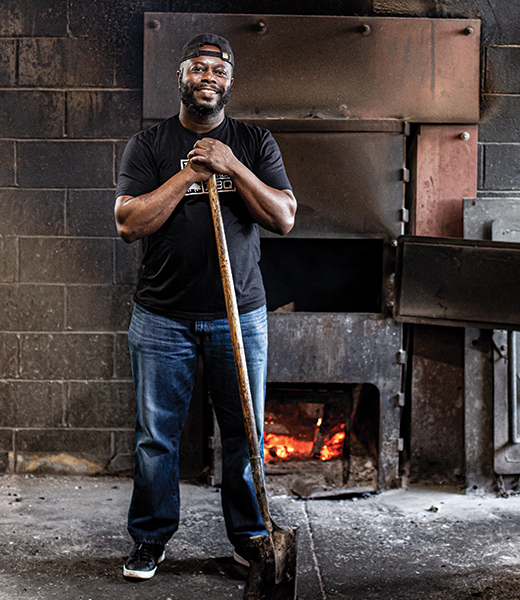 Rodney Scott standing in front of the smoker at his restaurant.