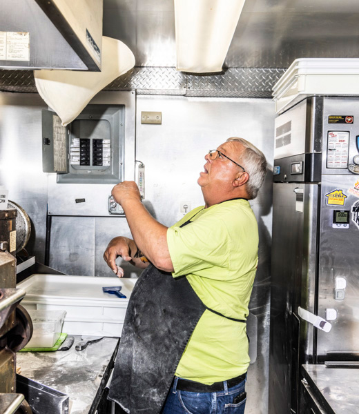 Glenn Allen tossing pizza dough inside his food truck