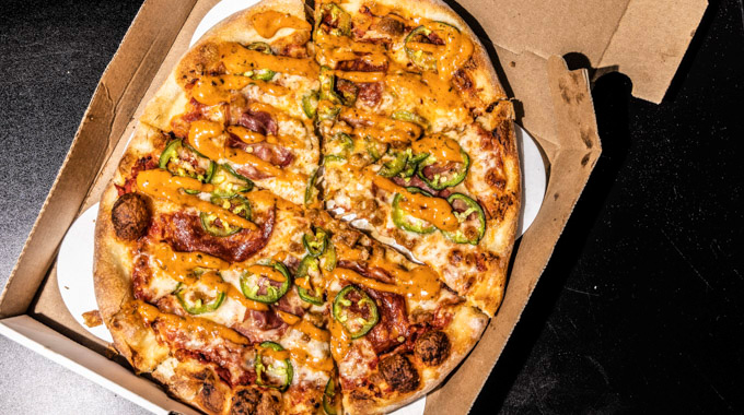 Flame and Pie Mobile Pizzeria's Flaming Pie, topped with jalapeños, Sriracha sausage, chorizo, and spicy red sauce