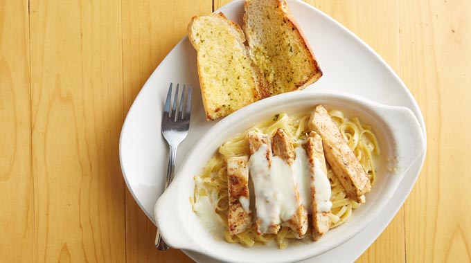 Chicken alfredo served with a side of garlic bread