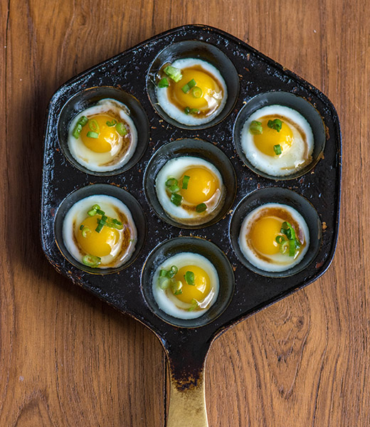 Quail eggs topped with soy sauce and scallions served in a pan