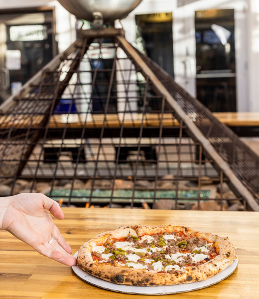 Someone reaching for a slice from Amore Neapolitan Pizzeria 