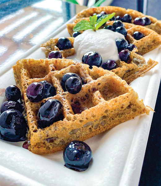 Amaranth waffles, topped with berries, a dollop of cream, and a mint sprig.