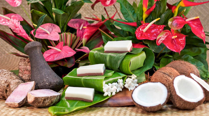 An arrangement of haulolo, flowers, split coconuts, and taro