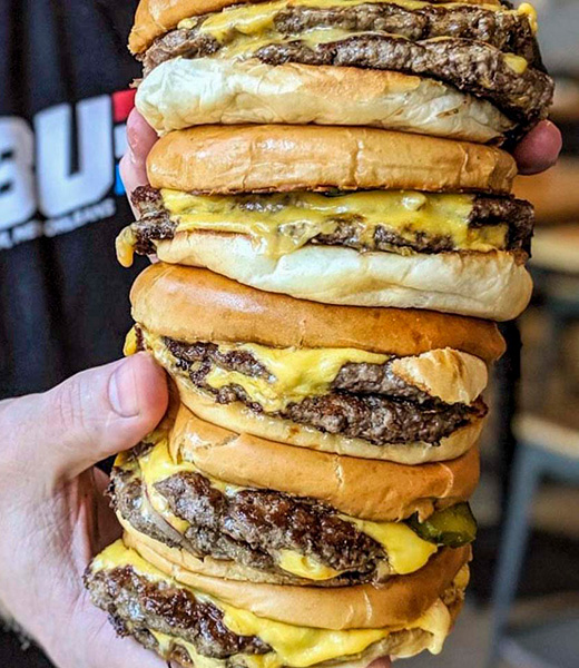 Someone holding up a stack of Company Burger Signature Burgers