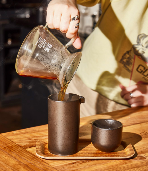 Barista pouring coffee into a carafe at Three Ships Coffee Roasters.