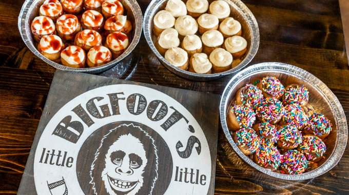 Three aluminum trays holding mini donuts with a variety of toppings
