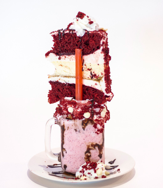 A milkshake topped with a large slice of red velvet cake