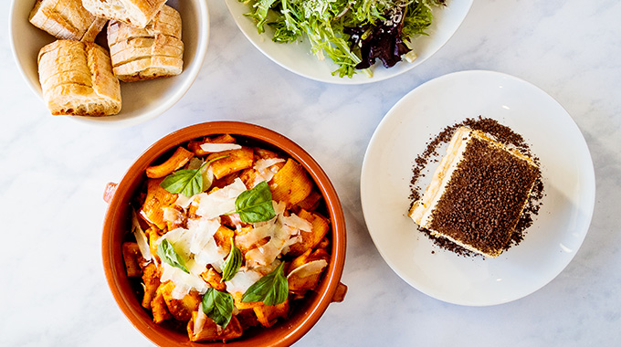 A spread with rigatoni Bolognese, salad, sliced bread, and tiramisu