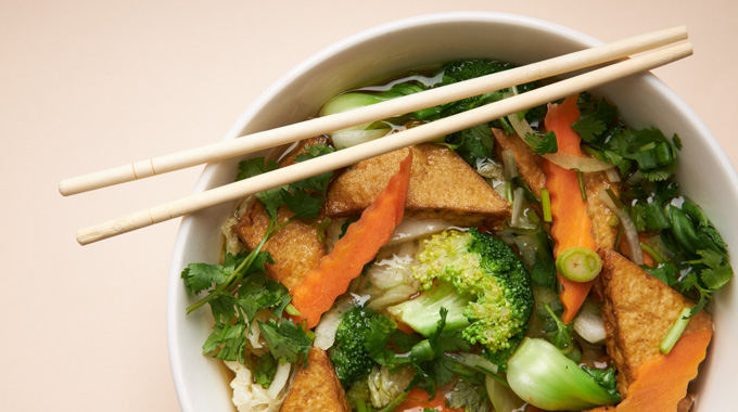 Pho topped with carrots, broccoli, and fried tofu